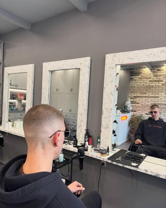 Κούρεμα skin fade από πίσω, με τους τρεις μαρμάρινους καθρέφτες του καταστήματος